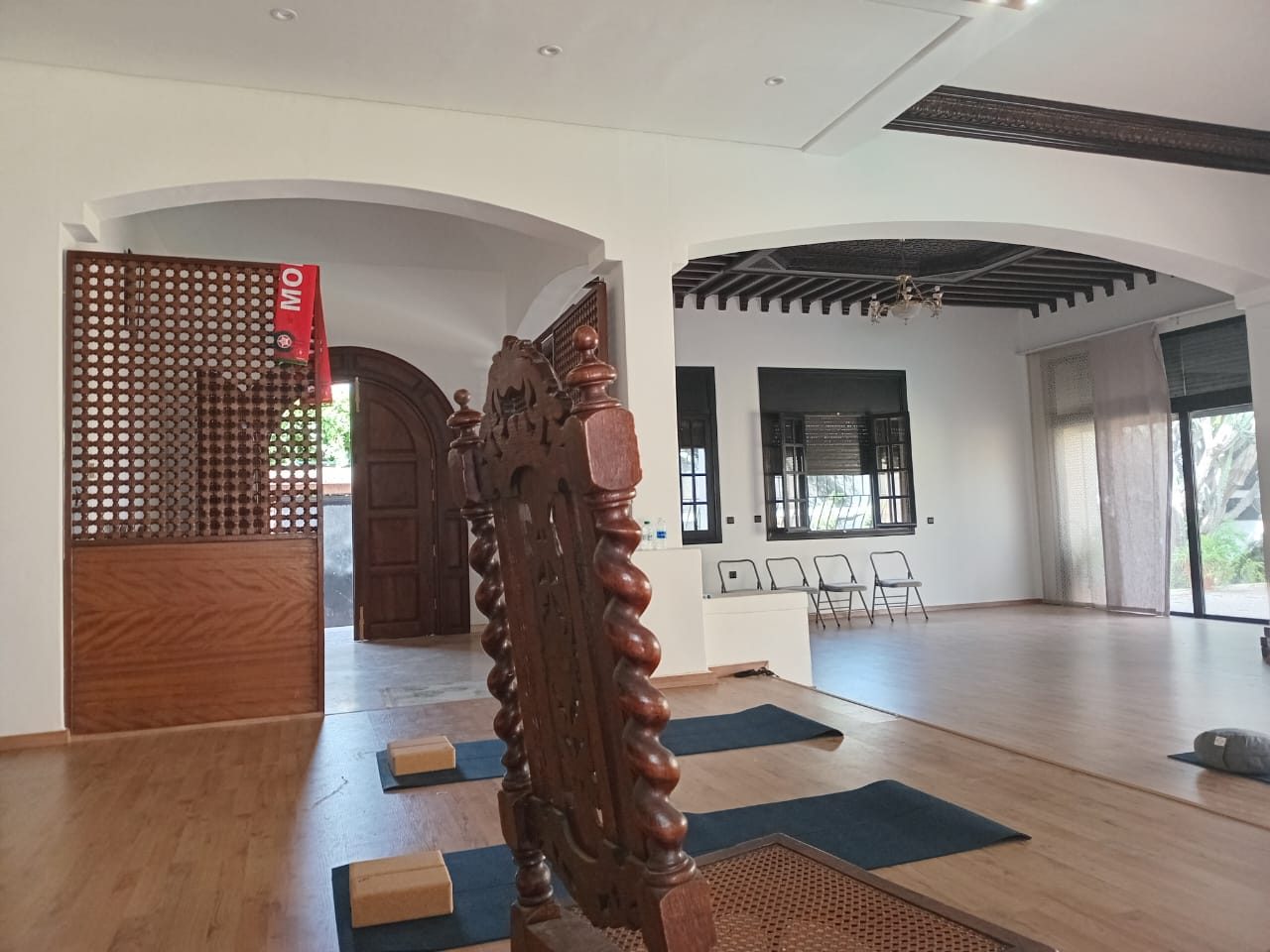 Salon voûté du centre de yoga à Casablanca, tapis installés sous les arcades et le plafond en bois peint
